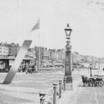 historic photograph of promenade with clock tower and large slash shape