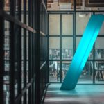 the hallway of a working space with floor to ceiling windows and blue illuminated slash