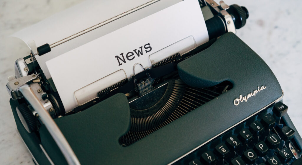 Image of a black type-writer with the word 'News' types on a white page.